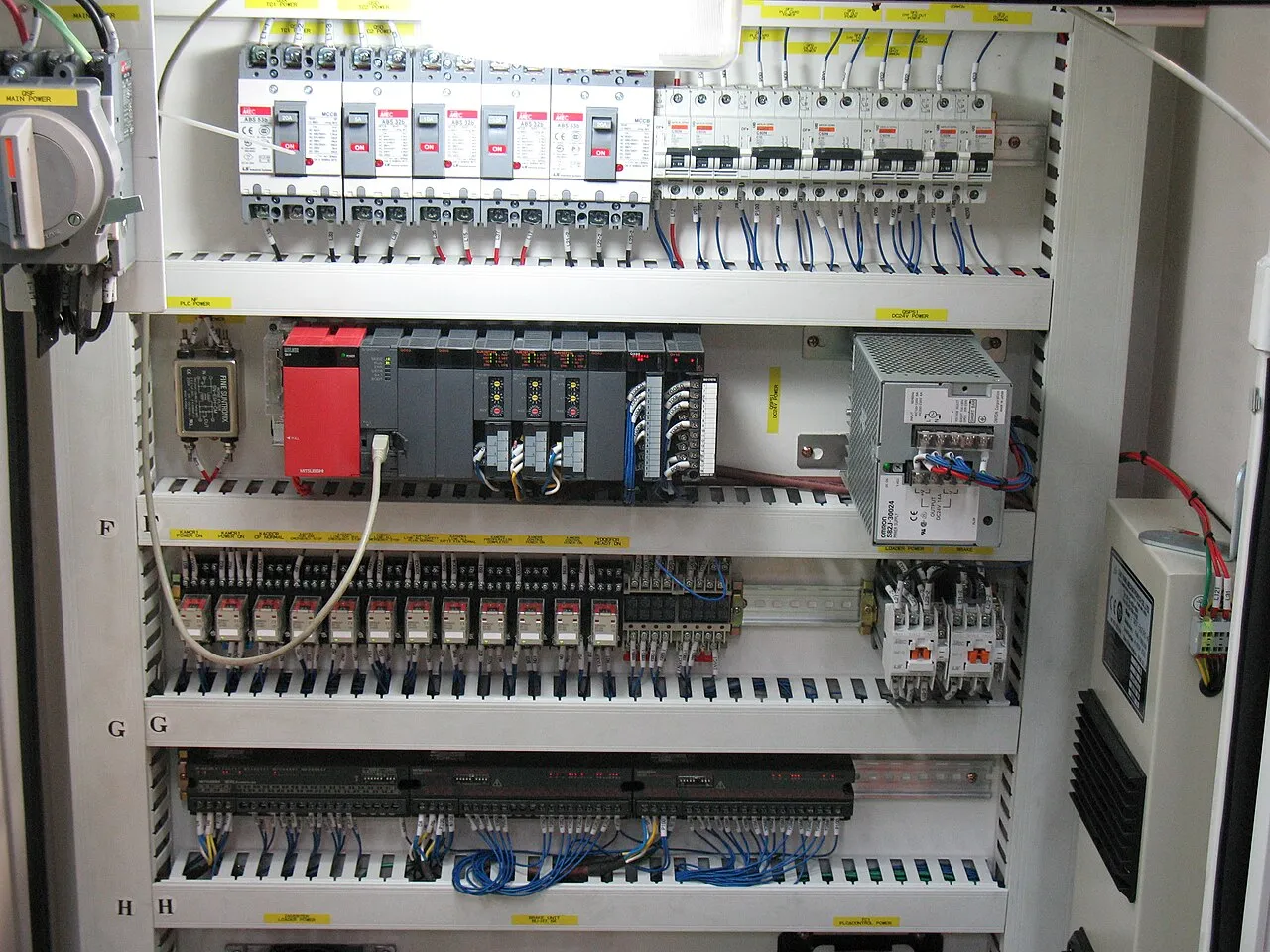 導入の流れ03 製作・実装(工場の制御盤に設置された三菱電機製PLC)